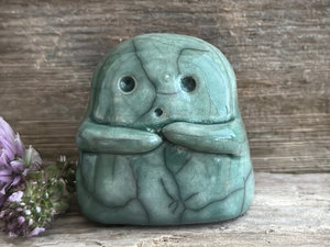 A sweet little kodama nature spirit ceramic guardian statue glazed in soft forest green and with a lovely, gentle face and little arms.