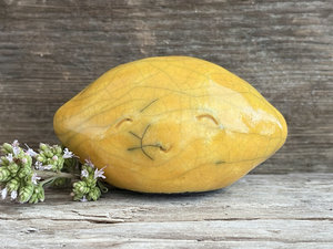 a very happy raku ceramic sculpture of a lemon. it's glazed in a golden yellow colour.
