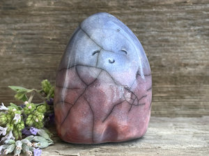 a small, kind of tall dome or egg-shaped raku ceramic sculpture of a woodland nature spirit. it has a happy, gentle face and is glazed in a top-to-bottom gradient of blue to purple to a soft, warm orangey mauve colour. (it’s actually really hard to describe the colours on this one as they all kind of overlap, but those are the main ones.)