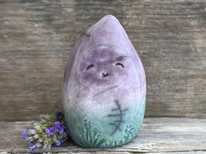 raku ceramic gnome spirit glazed in a bottom-to-top gradient of forest green to purple. it has a gentle, kind face, and there are flower and plant carvings around its base.