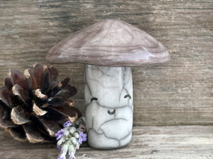 Cute mushroom raku ceramic sculpture with a very smiley face. Their stalk is glazed in creamy-white (this is where their face is) and their mushroom cap is brown.