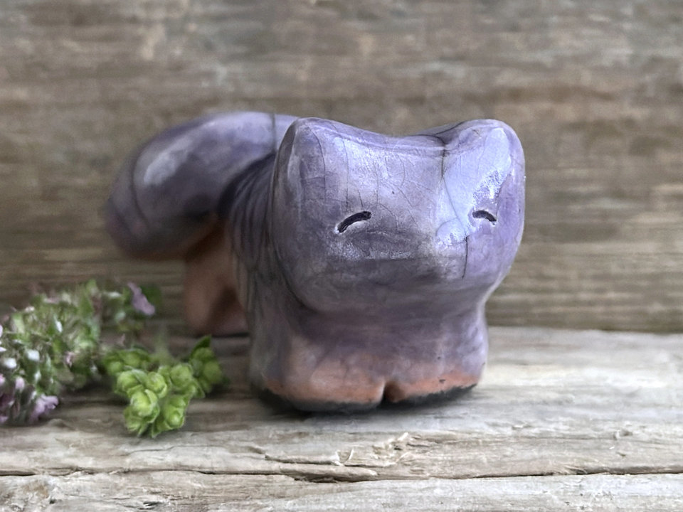 raku ceramic kitsune fox sculpture glazed in a top-to-bottom gradient of soft violet to peach. it has a kind, gentle face, and a tail curled over its back.