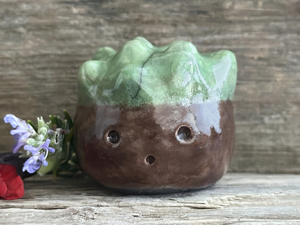 a roundish raku scuplture glazed in warm brown with green for the chestnut spikes on the top of its head. (they're not sharp at all!). it has a cute, open, friendly face.