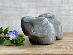 Little raku ceramic cat spirit kami sculpture glazed in grey. It has a kind, gentle, sleepy face, and its tail is curled over its back on its right.