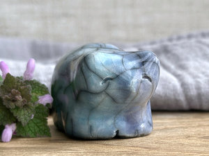 Ceramic raku bear kami sculpture glazed in turquoise mostly on its right side and blue mostly on its left side. It has a kind, gentle face and is a little chonky. there are tiny dark grey spiderweb patterns in the glaze, in addition to the normal raku crackles, from where raindrops fell on it.