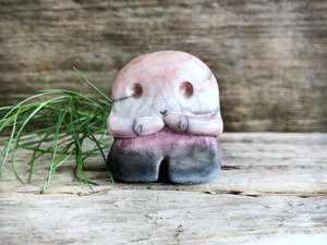 A sweet little nature spirit ceramic guardian statue glazed in the genderfluid flag pink, white, purple, black, and blue colours and with a lovely, gentle face and little arms. It has a small branch design carved up one side.