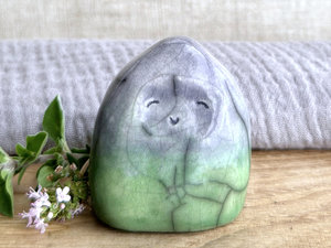vaguely dome-shaped nature spirit ceramic sculpture. it is glazed in a bottom-to-top gradient of spring green to pale violet. it has a gentle, smiling face.