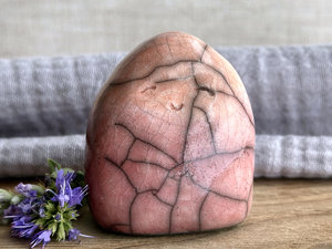 vaguely dome-shaped nature spirit ceramic sculpture. it is glazed in a bottom-to-top gradient of a soft bordeaux red to warm, soft orange. it has a gentle, smiling face.