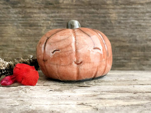 Raku ceramic orange pumpkin nature spirit kami sculpture with a very happy, smiley face.