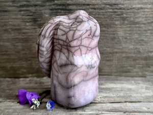 Raku ceramic usagi rabbit kami nature spirit glazed in a soft, pale pink-mauve colour with hints of violet. Its ears are folded down its back, and it has a kind, gentle face.