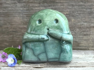 A sweet little kodama nature spirit ceramic guardian statue glazed in shades of green and with a lovely, gentle face and little arms.