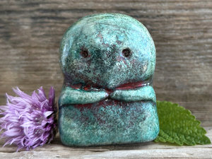 A kodama nature spirit ceramic guardian statue glazed in a turquoise and copper glaze. It has a wide face, two big eyes, and cute little arms.