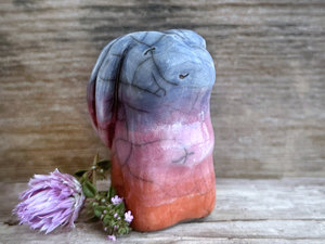 Raku ceramic usagi rabbit kami nature spirit glazed in a bottom-to-top gradient of burnt orange to mauve to indigo-violet. Its ears are folded down its back, and it has a kind, gentle face.