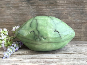 a very happy raku ceramic sculpture of a lime or a lemon. it's glazed in a soft bright green colour.