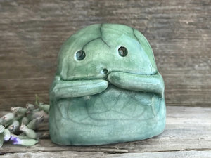 A sweet little kodama nature spirit ceramic guardian statue glazed in shades of green and with a lovely, gentle face and little arms.