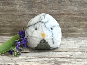 Raku ceramic little owl or owlet kami nature spirit statue glazed in white with a grey front. it has gentle eyes and a little yellow beak.