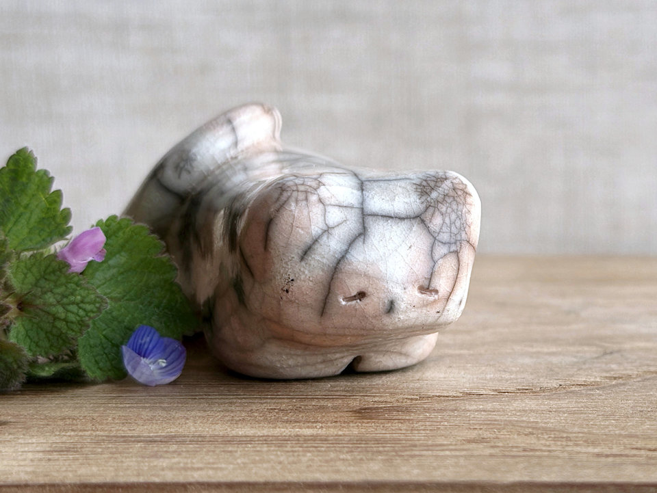 Little raku ceramic cat spirit kami sculpture glazed in pale orange and white and with a kind, gentle face. There are tiny dark grey spiderweb patterns in the glaze, in addition to the normal raku crackles, from where raindrops fell on it.