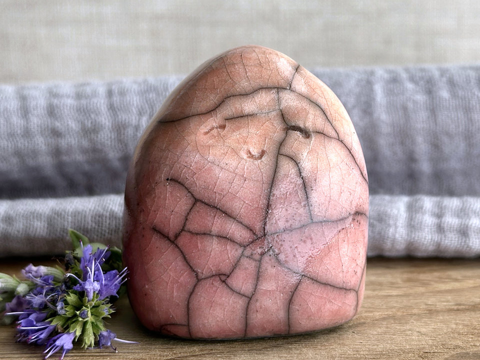 vaguely dome-shaped nature spirit ceramic sculpture. it is glazed in a bottom-to-top gradient of a soft bordeaux red to warm, soft orange. it has a gentle, smiling face.