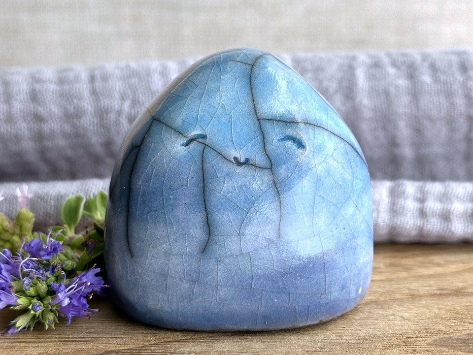 vaguely dome-shaped nature spirit ceramic sculpture. it is glazed in a bottom-to-top gradient of blue to soft turquoise. it has a gentle, smiling face.