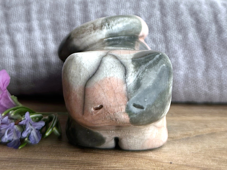 Little raku ceramic cat spirit kami sculpture glazed in a calico pattern (soft orange, grey, and white) and with a kind, gentle, and sleepy face.