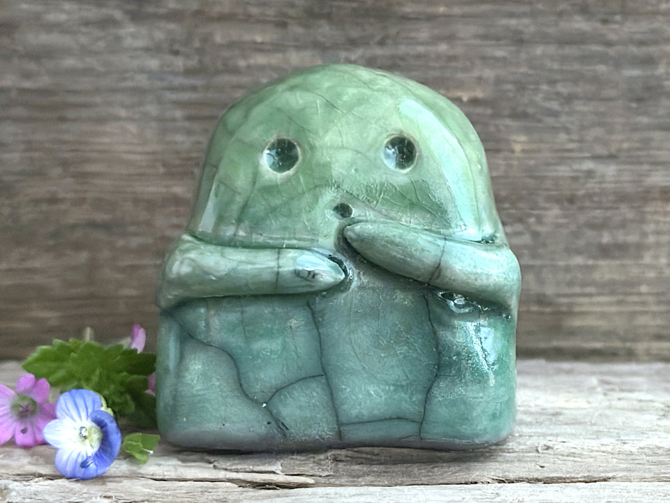 A sweet little kodama nature spirit ceramic guardian statue glazed in shades of green and with a lovely, gentle face and little arms.