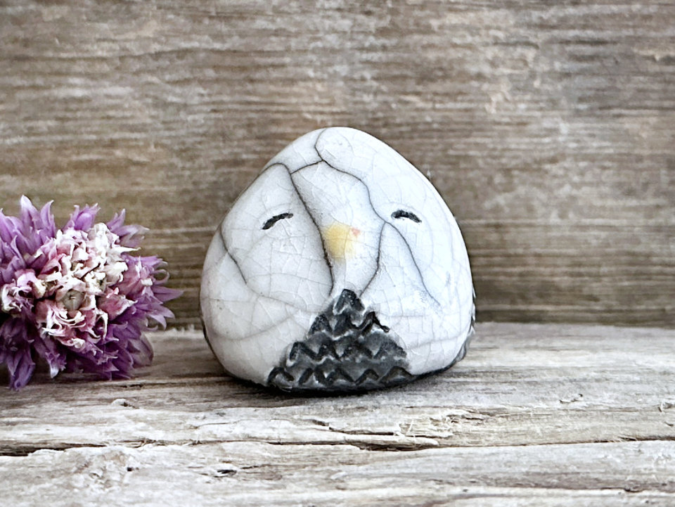 Raku ceramic little owl or owlet kami nature spirit statue glazed in white and grey with gentle, smiling eyes and a little yellow and orange beak.