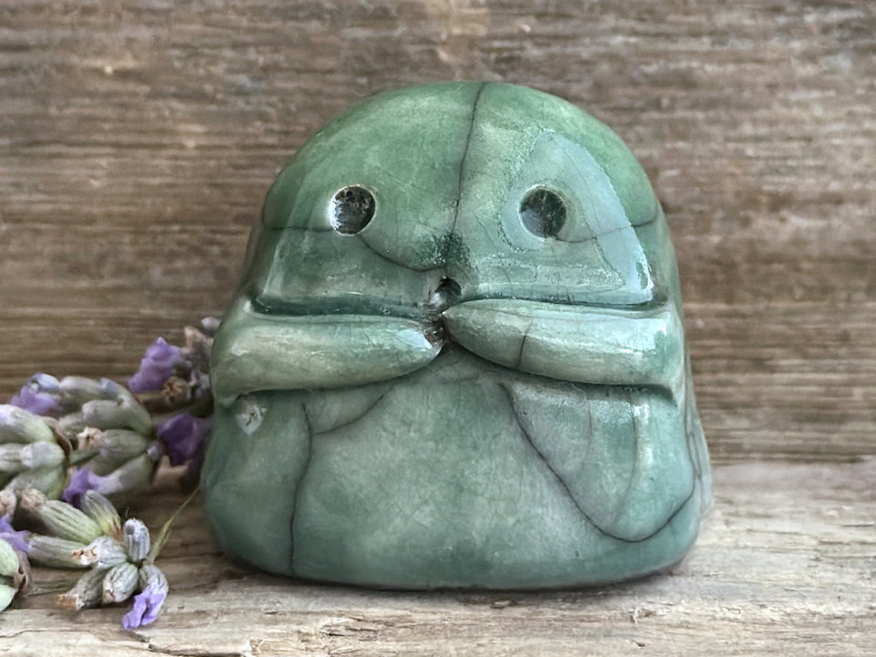 A sweet little kodama nature spirit ceramic guardian statue glazed in shades of green and with a lovely, gentle face and little arms.