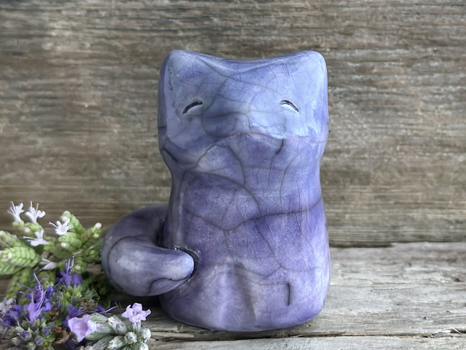 A calm and gentle Shinto Inari nighttime moon kitsune fox kami spirit ceramic raku statue glazed in a bottom-to-top gradient of violet to blue. Its tail is curled around the right side of its body, and it has a kind face.