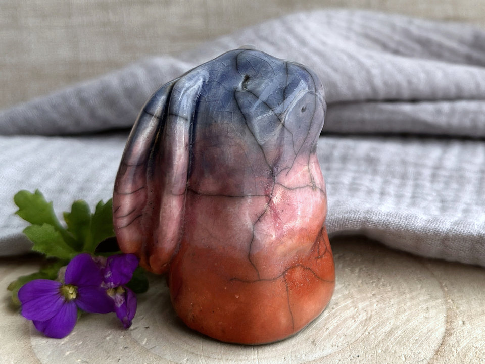 Raku ceramic usagi rabbit kami nature spirit glazed in a bottom-to-top gradient of burnt orange to mauve to soft indigo. Its ears are folded down its back, and it has a kind, gentle face.