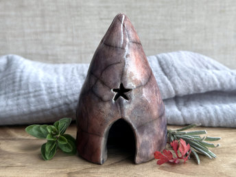 Raku spirit cave with with an arched door, a star window above it, and another window around the side. It's glazed in a variety of colours: soft warm orange, violet and purple, indigo, mauve, and soft deep red.