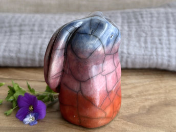 Raku ceramic usagi rabbit kami nature spirit glazed in a bottom-to-top gradient of burnt orange to mauve to blue-violet. Its ears are folded down its back, and it has a kind, gentle face.