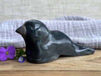  Raku ceramic sculpture of a sitting raven. It is glazed in dark blue-grey, and its beak is left natural, unglazed black.