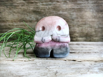 A sweet little nature spirit ceramic guardian statue glazed in the genderfluid flag pink, white, purple, black, and blue colours and with a lovely, gentle face and little arms. It has a small branch design carved up one side.