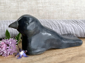  Raku ceramic sculpture of a sitting raven. It is glazed in dark blue-grey, and its beak is left natural, unglazed black.