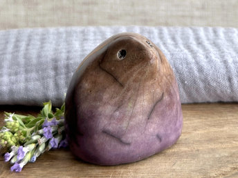 a lovely-to-hold little sculpture of a stylised mole friend. a bit like a large raindrop with a pointy nose? it's glazed in a bottom-to-top gradient of purple to warm brown and has a kind, gentle face.