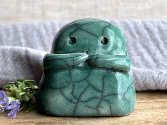 A sweet little kodama nature spirit ceramic guardian statue glazed in forest green and with a lovely, gentle face and little arms.