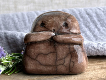 A sweet little kodama nature spirit ceramic guardian statue glazed in brown and with a lovely, gentle face and little arms.