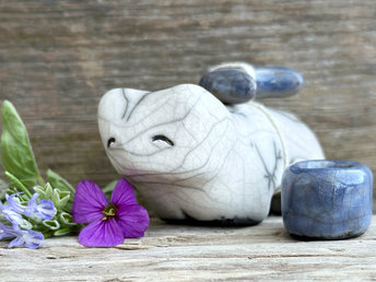 Raku ceramic white bear sculpture with a kind, gentle face. It carries a blue ceramic crescent moon on its back and has a little blue bowl too.