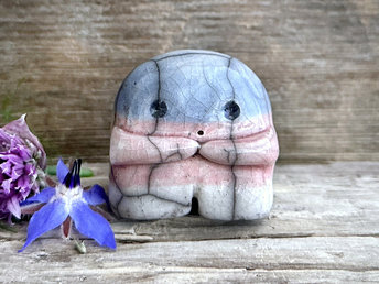 A sweet little nature spirit ceramic guardian statue glazed in the transgender pink, white, and blue colours and with a lovely, gentle face and little arms. It has a small branch design carved up one side.