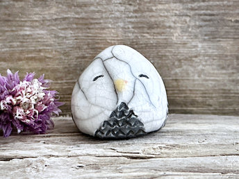 Raku ceramic little owl or owlet kami nature spirit statue glazed in white and grey with gentle, smiling eyes and a little yellow and orange beak.
