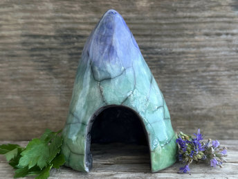 Raku spirit cave glazed in a bottom-to-top gradient of spring green to forest green to blue. It has a large, domed opening at its front.