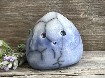 small cloud raku ceramic sculpture glazed in blue with a white top. it has an adorable, happy face and is shaped vaguely like a squat raindrop.