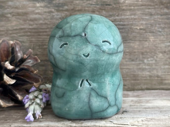 a smiley and loving Jizo Shinto raku ceramic sculpture talisman glazed in forest green. they have a kind, gentle face and are a wonderful smooth shape to hold in the hand.