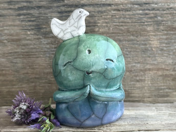 a shinto jizo nature spirit guardian raku ceramic sculpture glazed in a bottom-to-top gradient of blue to forest green to spring green. they have a happy, smiley face, little praying hands, and a sweet white bird on their head.