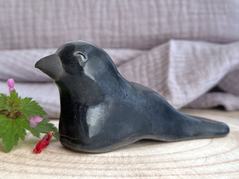  Raku ceramic sculpture of a sitting raven. It is glazed in dark blue-grey, and its beak is left natural, unglazed black.