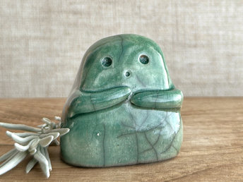 A sweet little kodama nature spirit ceramic guardian statue glazed in shades of green and with a lovely, gentle face and little arms.